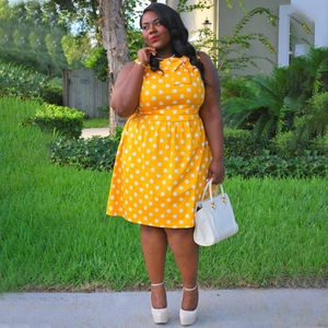 Detail of yellow polka dot dress featuring a sleeveless round neck with a decorative bow