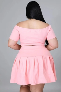 Rear view of pink off-shoulder crop top and pleated mini skirt set on a grey background