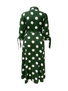 Detail view of dark green polka dot dress with tied cuffs and waistband from behind