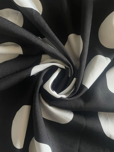 Detail of black and white polka dot fabric with elegant spiral texture and silky finish