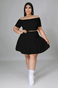 Detail of off-shoulder black two-piece set with pleated high waist mini skirt