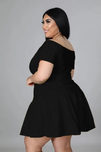 Side view of black short-sleeved crop top and high-waisted pleated skirt set for plus size