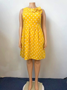 Detail view of the yellow retro sleeveless dress featuring white polka dots and a bow neckline