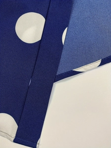 Macro detail of dark blue fabric with white polka dots showing neat stitched seams