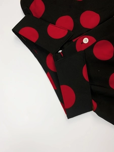 Detailed view of black polka dot shirt sleeve with contrast white buttons and lapel
