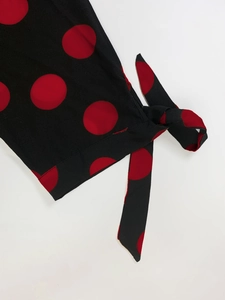 Detailed view of the red polka dot fabric and side tie bow on the black long sleeve dress