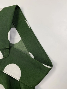 Close-up detail of dark green polka dot shirt collar with professional stitching quality