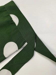 Detailed close-up of green and white polka dot fabric texture with fine stitching