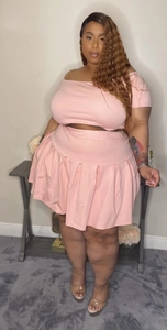 Detail view of pink two-piece set featuring off-shoulder top and high waist pleated skirt