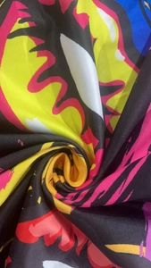 Close-up of vibrant abstract printed fabric with silky texture and draped folds