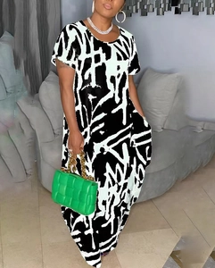 Short sleeve maxi dress with black and white abstract print and green woven bag
