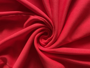 Gros plan détaillé montrant la texture et le drapé doux du tissu tricoté rouge vif