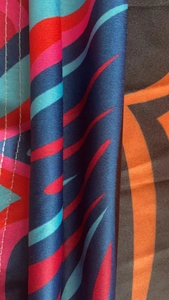 Close-up detail of smooth knit fabric with abstract geometric wave pattern and white stitching