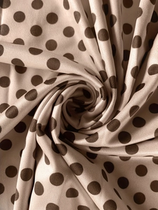 Detailed close-up of champagne polka dot fabric with smooth silk texture and drape