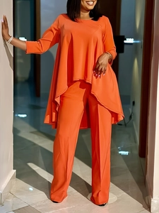 Détail d'un ensemble orange deux pièces avec haut asymétrique et pantalon taille haute