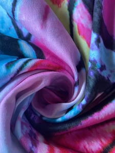 Makroansicht von weichem Batikstoff mit lebhaften abstrakten Mustern in Pink und Violett