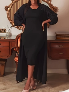 Detail of elegant black two-piece set featuring long cardigan and slimming dress on model
