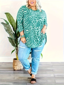 Detailed view of women's plus size green leopard print top with distressed denim jeans