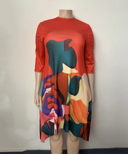 Detailed view of bright orange dress with abstract colorful patterns and irregular hemline