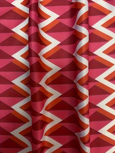 Macro detail of the plus size dress fabric with vibrant orange and red zigzag patterns