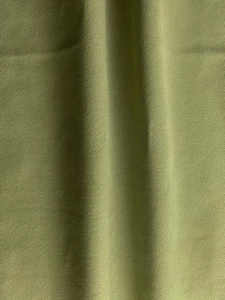 Close-up of olive green fabric featuring a distinct granular texture and soft natural draping