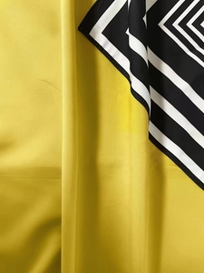 Detail of loose fit dress showing yellow fabric texture and black striped geometric edge