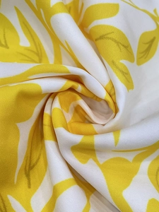 Detailed view of white and yellow floral print fabric with twill texture and soft finish