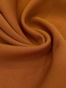 Macro shot of fine knit fabric in caramel color with detailed weaving texture and soft drape