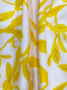 Detail of white fabric with yellow leaf prints showing soft texture and drape