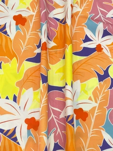 Detailaufnahme des tropischen Blattmusters in Orange, Lila und Blau auf leichtem Stoff