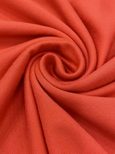 Close-up of soft orange-red knit fabric showing fine texture and smooth drape
