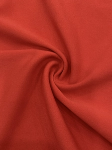 Macro detail of the red knitted fabric texture showing soft cotton blend fibers and weave
