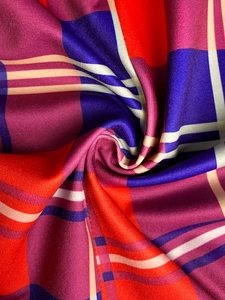 Close-up of vibrant red, blue and purple plaid fabric texture with elegant folds