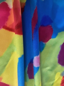 Macro detail of abstract watercolor printed fabric showing vivid multi-colored twill texture