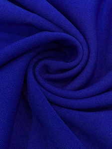 Macro detail of royal cobalt blue chiffon fabric with elegant spiral folds and fine texture