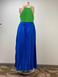 Dettaglio del top allacciato al collo verde smeraldo e gonna a pieghe blu reale su manichino
