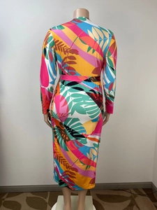 Back view of a long sleeve maxi dress featuring tropical leaf patterns and a waist tie
