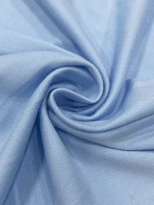 Detailed close-up showing the elastic texture and drape of light blue knitted fabric