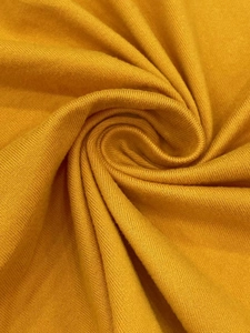 Close-up of ginger yellow knit fabric texture showing the soft fine plain weave pattern