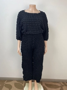 Detail of black two-piece set featuring textured popcorn fabric and three-quarter sleeves