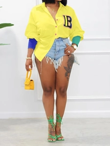 Detail of a bright yellow shirt with letter B patch and asymmetric color-block cuffs