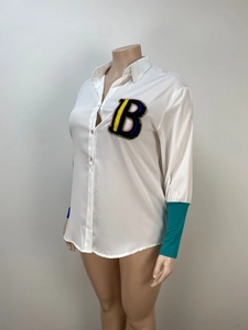 Close-up of white oversized shirt with colorful B letter patch and contrast cuffs