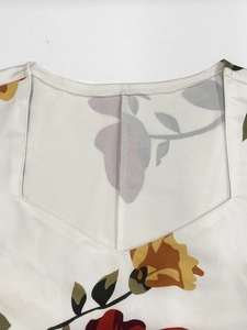 Détail de robe blanche à fleurs montrant le décolleté en V et le motif de roses