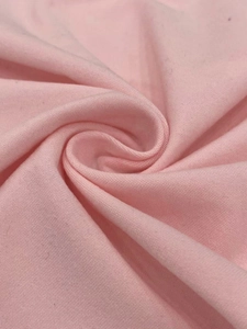 Macro shot of light pink knitted fabric texture showing soft material detail and draping