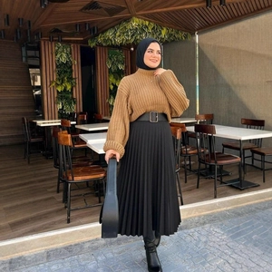 Tenue femme avec pull marron à col roulé, jupe plissée noire et ceinture à la taille