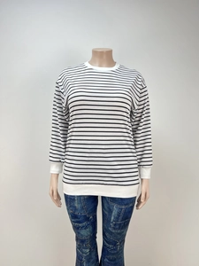 Detail of black and white striped long sleeve top with ribbed neckline and hem decoration