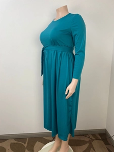 Peacock blue long-sleeve maxi dress with a high waist, tie belt, and pleated skirt design