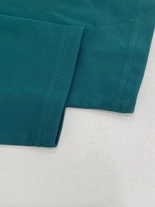 Detail of teal knit dress showing double-stitched hem and high-quality fabric texture