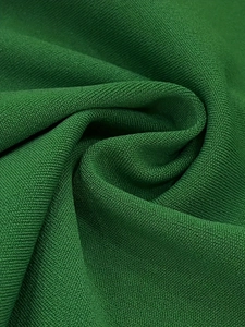 Close-up detail of green knitted fabric texture with fine weave pattern and soft drape