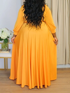 Detailed back view of a long orange maxi dress featuring wide hem and flowing pleated drape